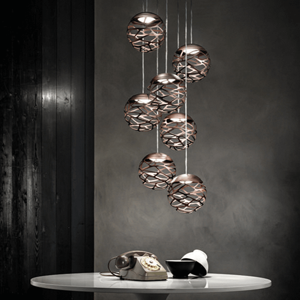 Lodes Kelly Cluster Sphere LED Pendellampe in metallischem Design, kreativ angeordnet über einem Tisch.