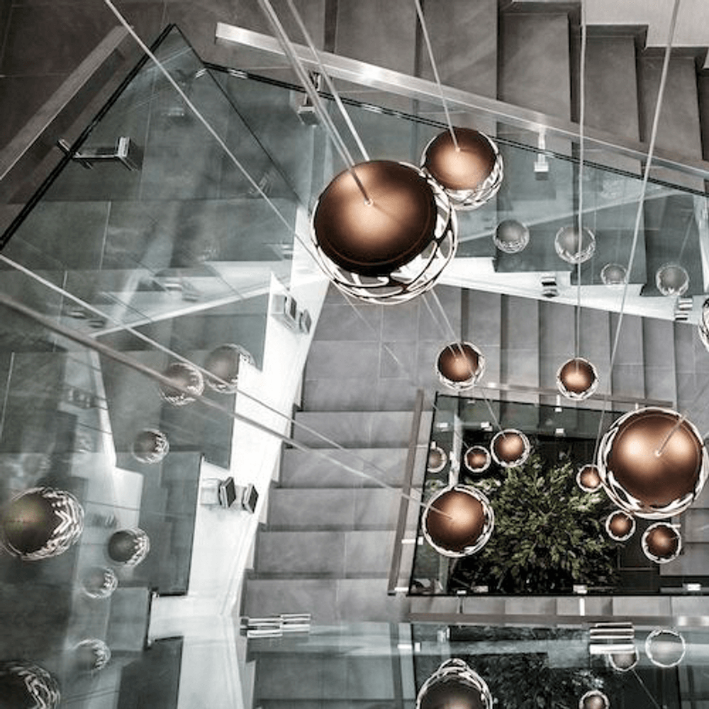 Lodes Kelly Cluster Sphere LED Pendellampe in modernem Treppenhaus-Design mit reflektierenden Oberflächen.