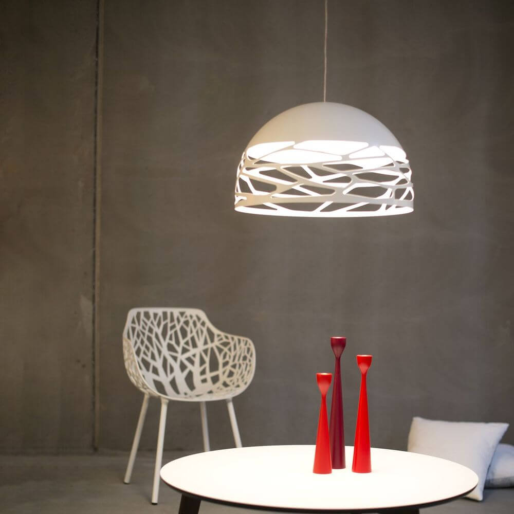Lodes Kelly Dome Hängelampe über einem Tisch mit modernen Vasen und einem weißen Stuhl im Hintergrund.