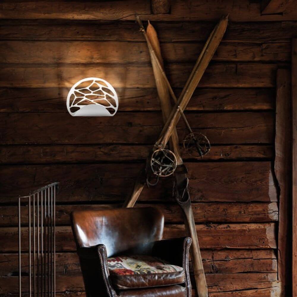 Lodes Kelly Wandlampe an einer Wand in einem rustikalen Interieur mit Holzverkleidung.