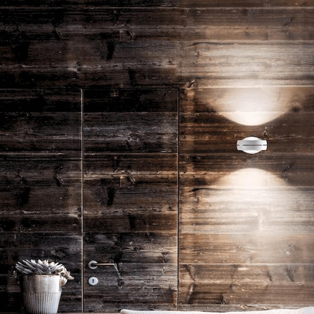 Lodes Nautilus LED Wandlampe 2300 Lumen an einer holzverkleideten Wand mit moderner Einrichtung