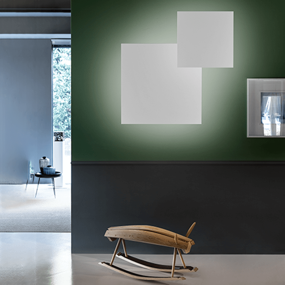 Lodes Puzzle Mega Square Small Wand- & Deckenlampe Weiß an einer grünen Wand mit geometrischen Formen.