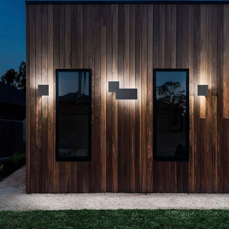 Lodes Puzzle Outdoor Single Square LED wall light installed on a wooden facade, creating soft evening lighting.
