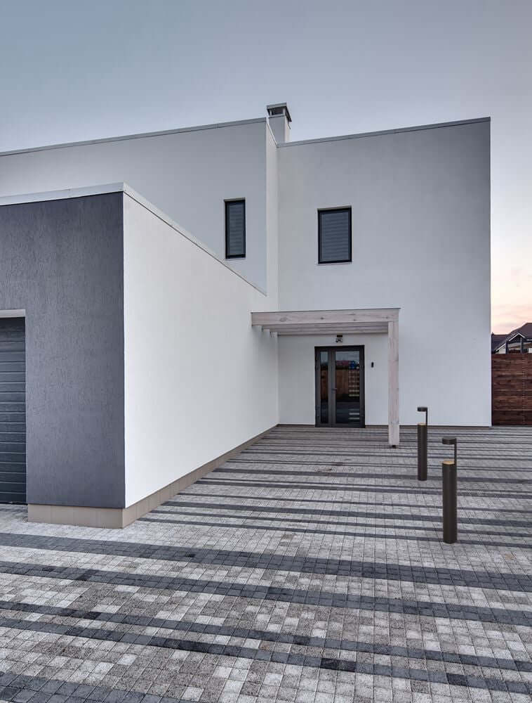 Moderne Architektur eines Hauses mit stilvollem Eingangsbereich und Pflasterstein-Parkplatz.