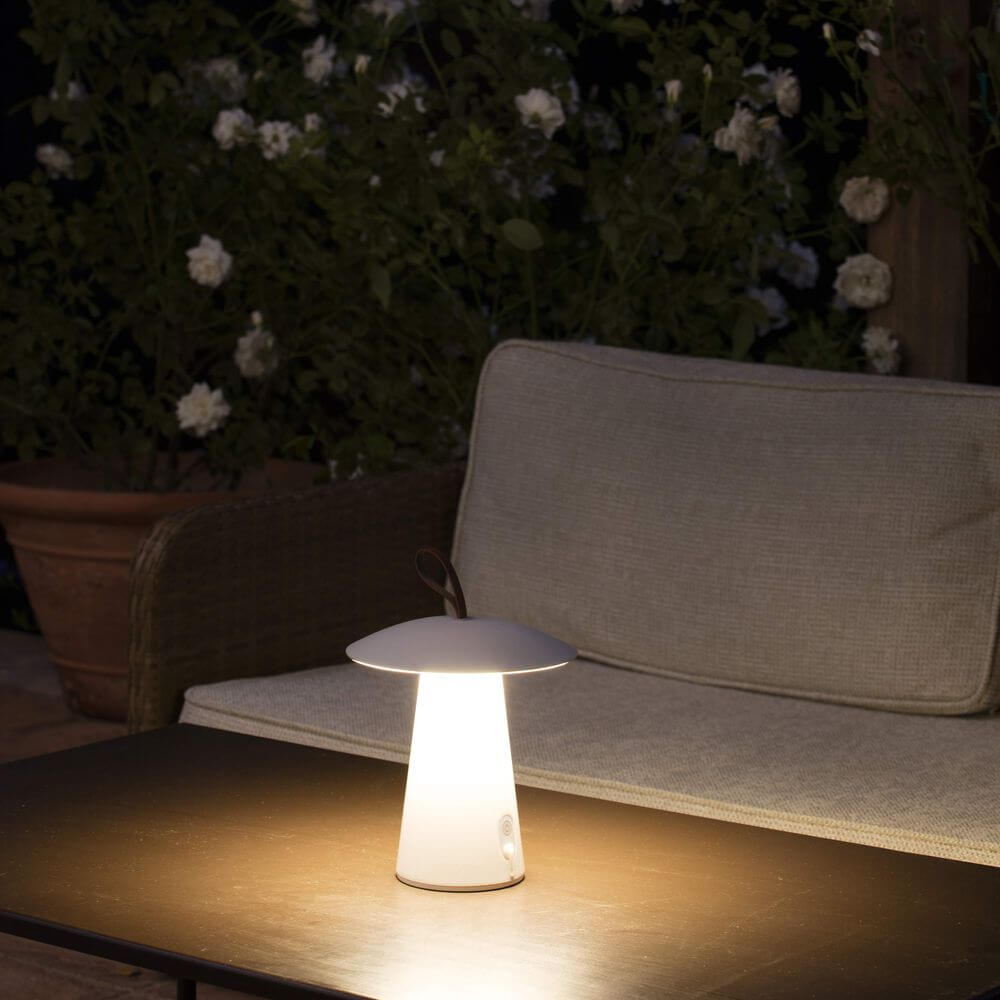 Task Outdoor LED-Tischlampe USB IP54 Weiß auf einem Tisch in einem Garten. Warmes Licht und pilzförmiges Design.
