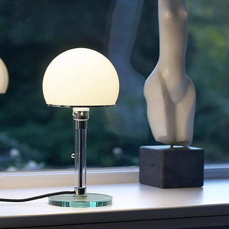 Tecnolumen Bauhaus bordlampe WG24 Wilhelm Wagenfeld på et bord ved siden af en skulptur.