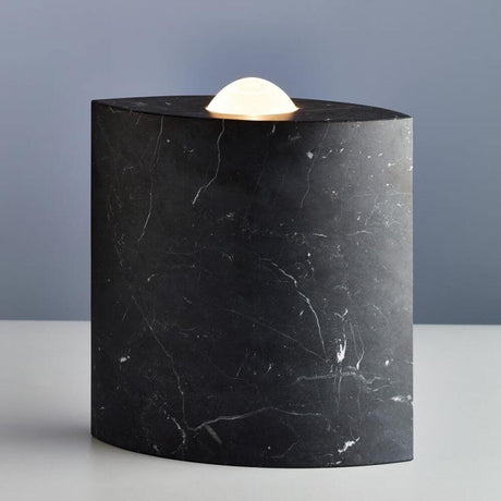 Tecnolumen gulvlampe Egyptian Eye Marmor Svart-Polert på et bord med elegant belysning.