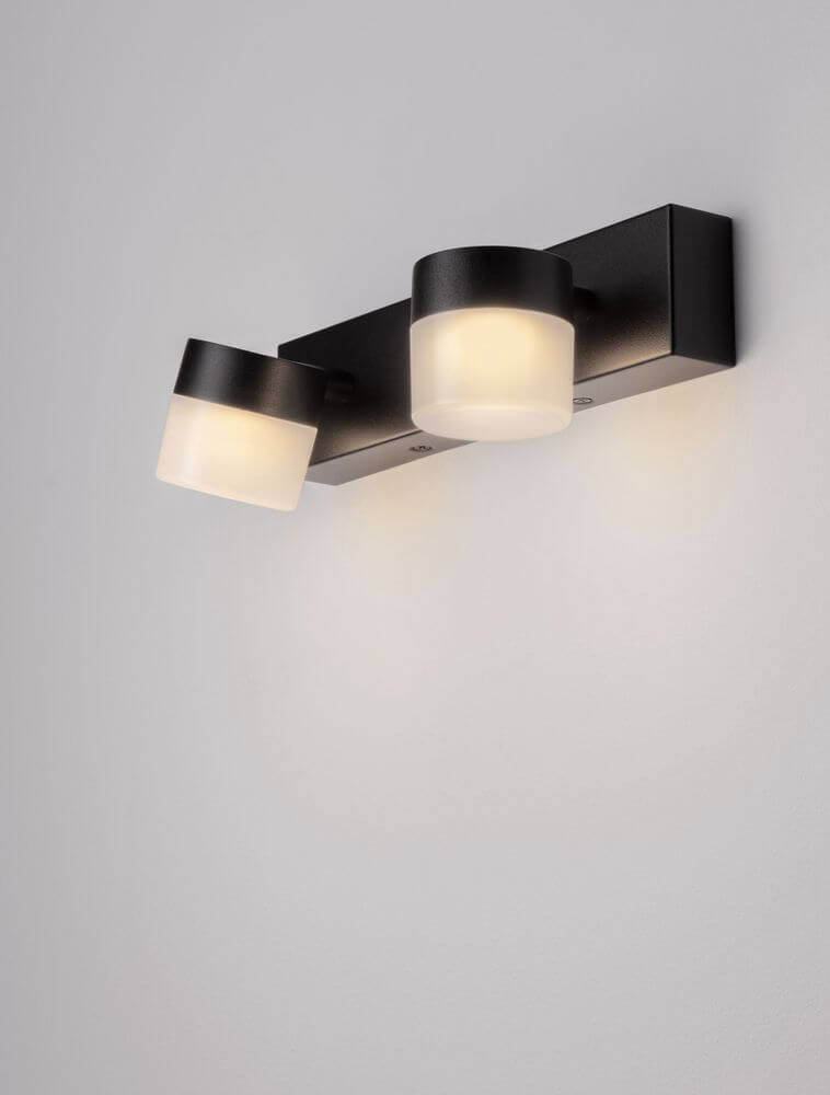 Teko LED Wandleuchte 2-flammig 3000K Schwarz IP44 an Wand montiert mit zwei runden Lampenschirmen.