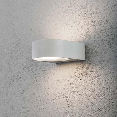 Aplique de parede exterior Teramo Cinza, vidro opalescente montado numa parede cinza, emite uma luz suave.