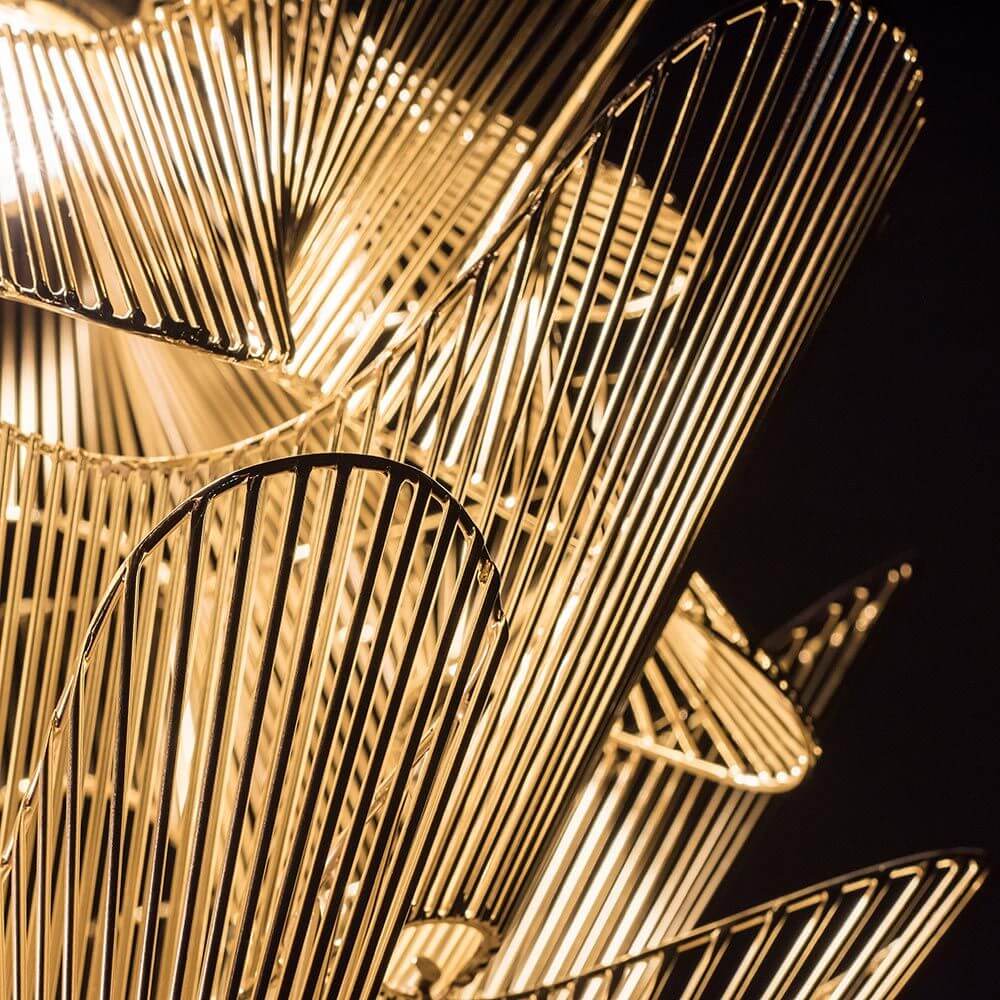 Detailansicht der Terzani Moiré Design Kronleuchter mit wellenförmigen, goldenen Stahlstreifen.