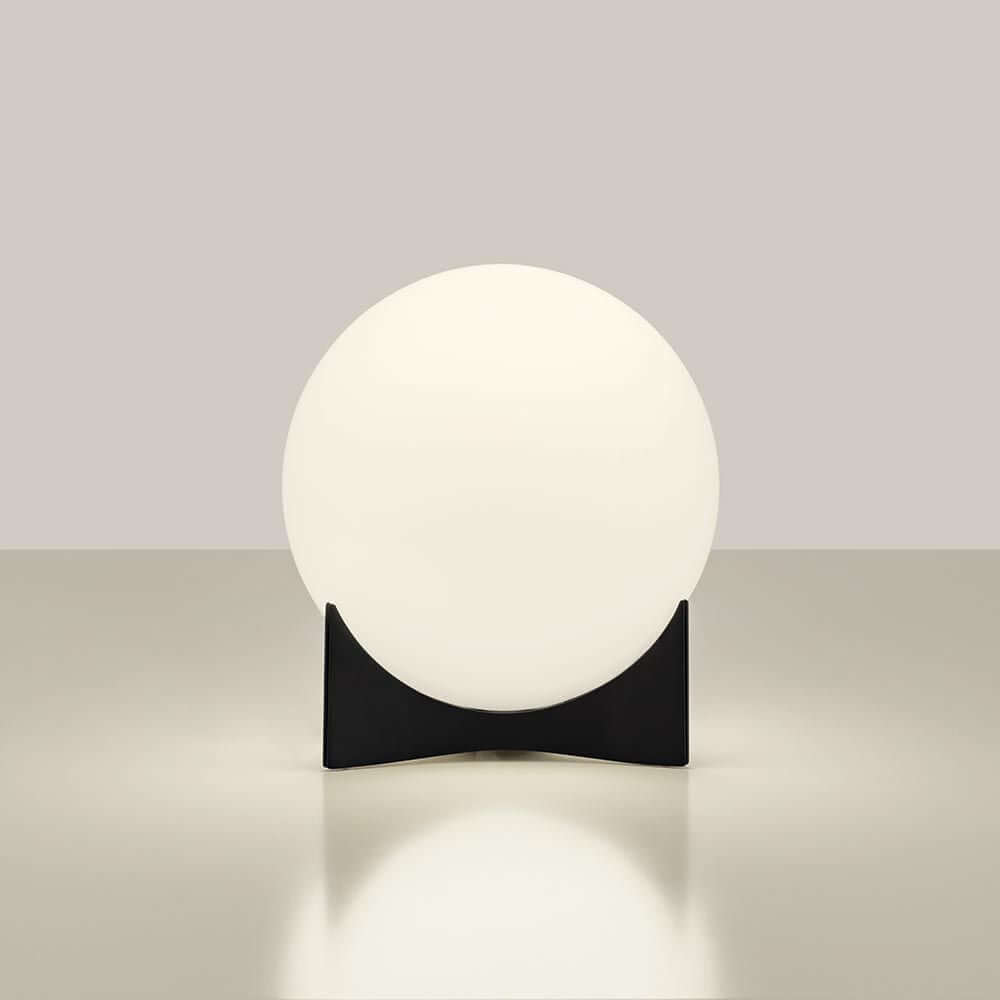 Terzani Oscar Design-Tischlampe mit runder Glasoberfläche und schwarzem Fuß auf einem minimalistischen Tisch.