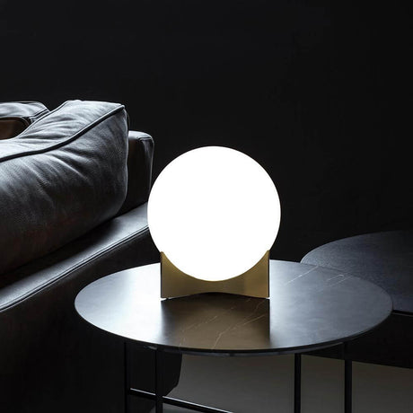 Terzani Oscar design table lamp on a table with a black background and sofa cushions.