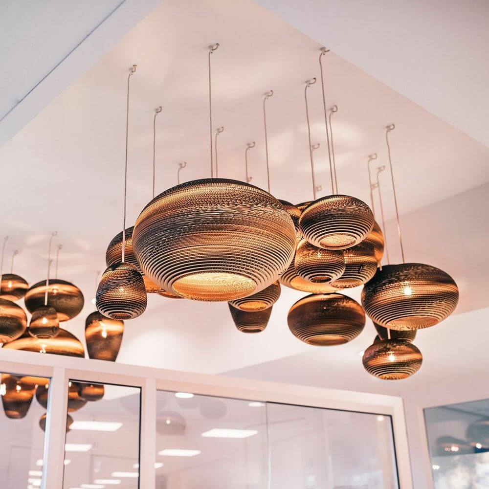 Jazzy Hängelampe aus Karton im ovalen Design, nachhaltig und modern, schwebend im Raum.