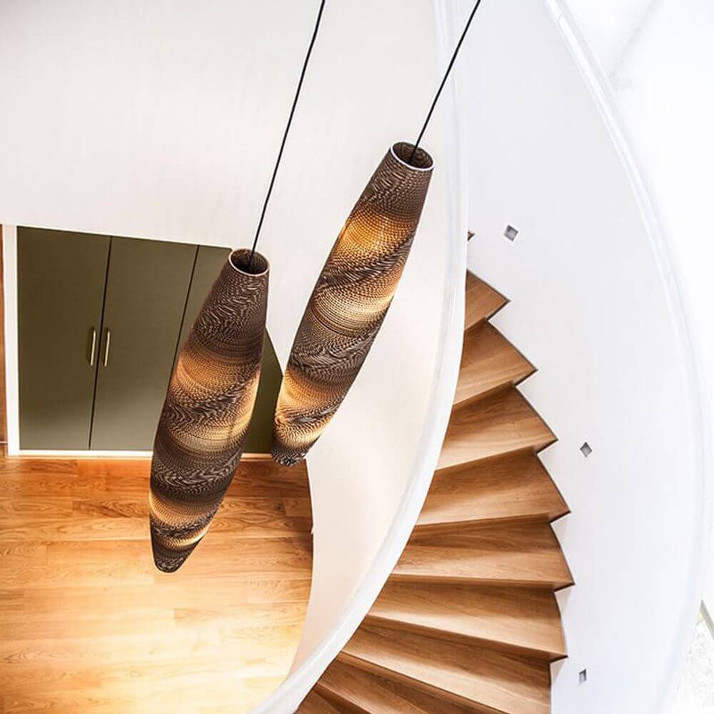 Hängende ovale Pendelleuchte aus Pappe im modernen Treppenhaus, nachhaltig und elegant gestaltet.