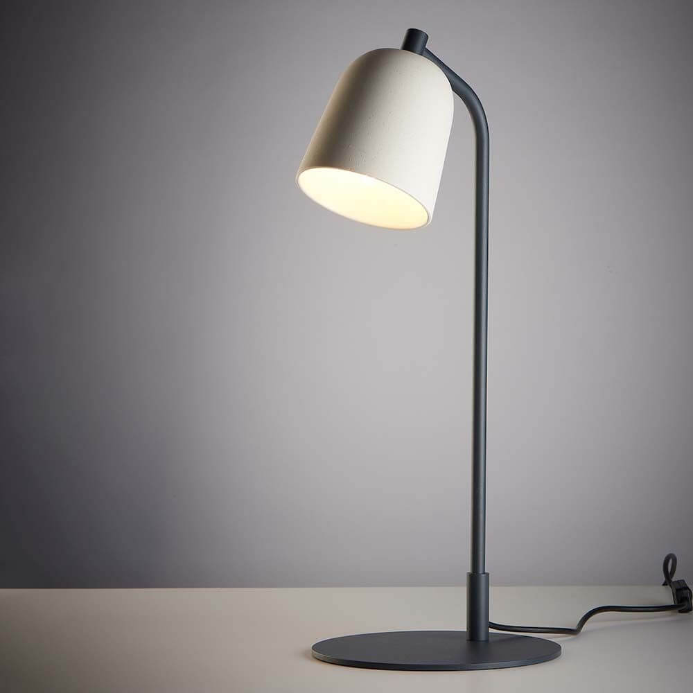 Casablanca Tischlampe Clavio Ø 12cm auf einem Tisch, modernes Design mit grauem Gestell und weißem Lampenschirm.