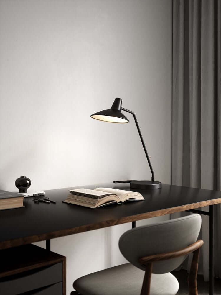 Tischlampe Darci auf einem Schreibtisch, ideal für funktionales Licht beim Lesen oder Arbeiten.