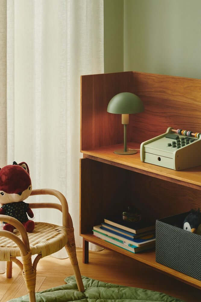 Tischlampe Ellen Mini auf einem Regal in einem skandinavisch eingerichteten Kinderzimmer mit Spielzeug.