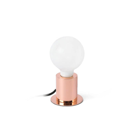 Lampe de table TEN cuivre avec source lumineuse ronde sur un socle en cuivre.