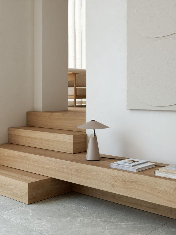 Tischlampe Taido elegant auf einer Holztreppe mit minimalistischer Einrichtung.