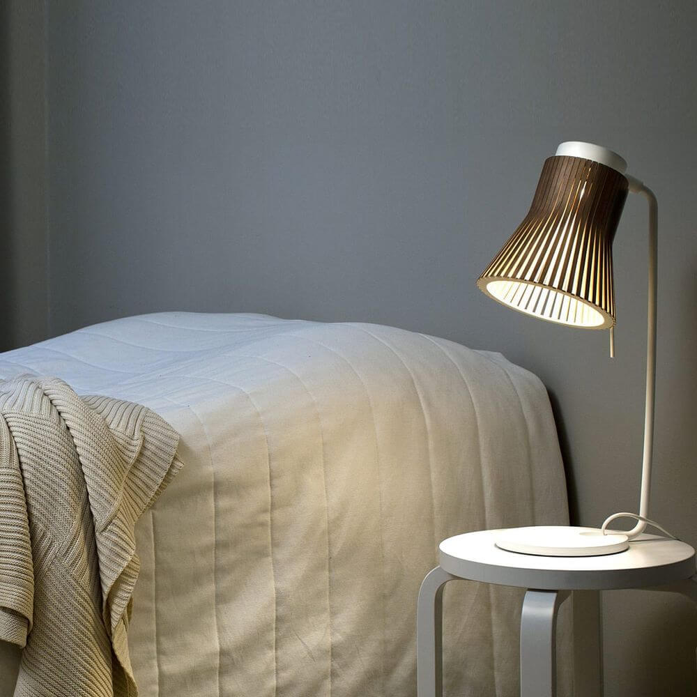 Tischleuchte Petite 4620 aus Holz 56cm auf Nachttisch neben Bett, weiches Licht verbreitend.