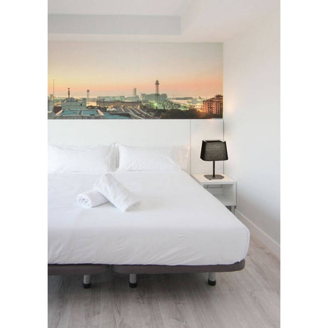 Tischleuchte SWEET Schwarz neben einem Bett in einem modern eingerichteten Schlafzimmer.