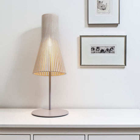 Secto 4220 table lamp made of wood, 75 cm, on a table with pictures in the background.