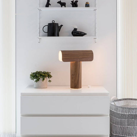 Table lamp Teelo 8020 made of wood 38 cm on a table with plants and decorations in the background.