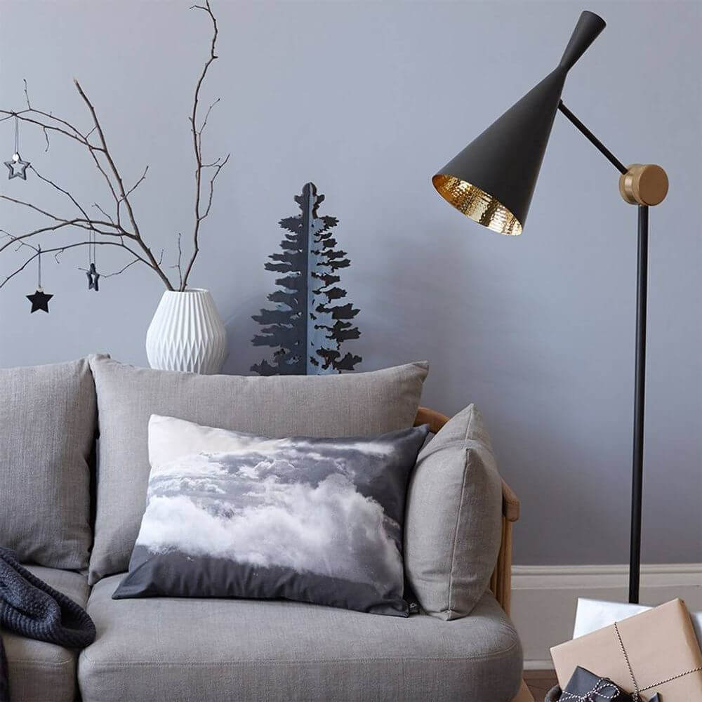 Tom Dixon Beat Stehleuchte verstellbar im modernen Wohnzimmer mit Couch und Kissen.