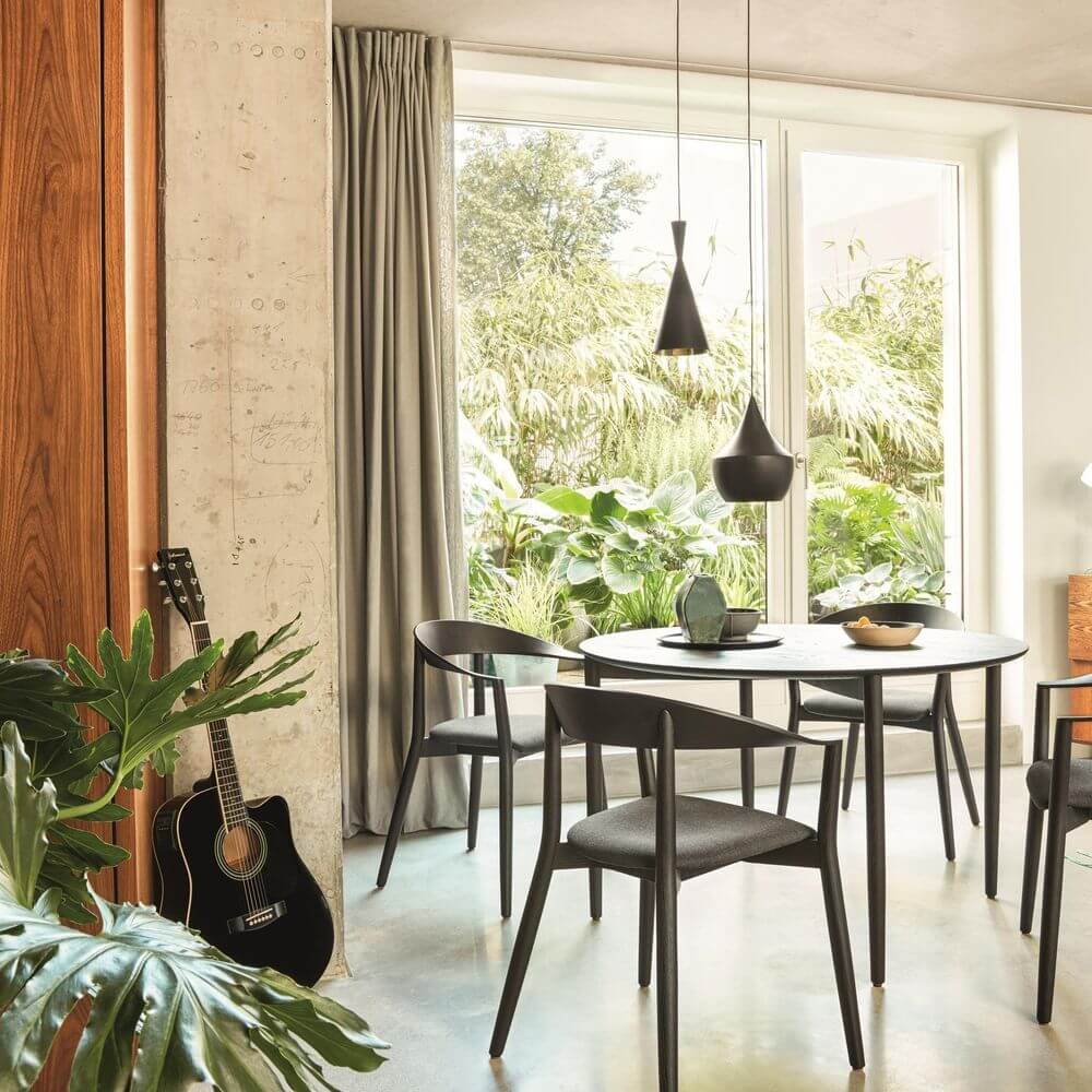 Tom Dixon Beat Tall LED Hängelampe Ø 19cm über einem Esszimmertisch in modernem Interieur, umgeben von Pflanzen.