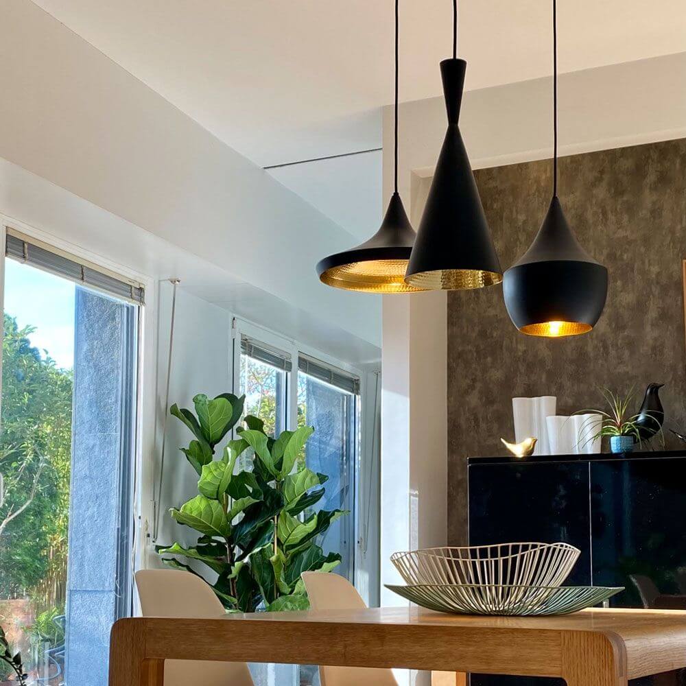 Tom Dixon Beat Wide Hängeleuchten im Innenraum, kombiniert mit grünen Pflanzen und modernem Mobiliar.