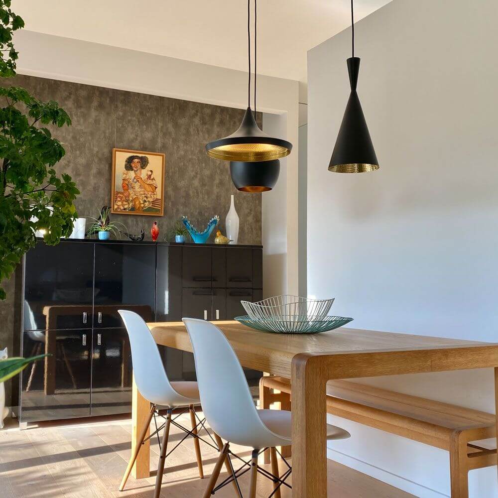 Moderne Esszimmerdekoration mit Tom Dixon Beat Wide Hängeleuchten und Holzstühlen.