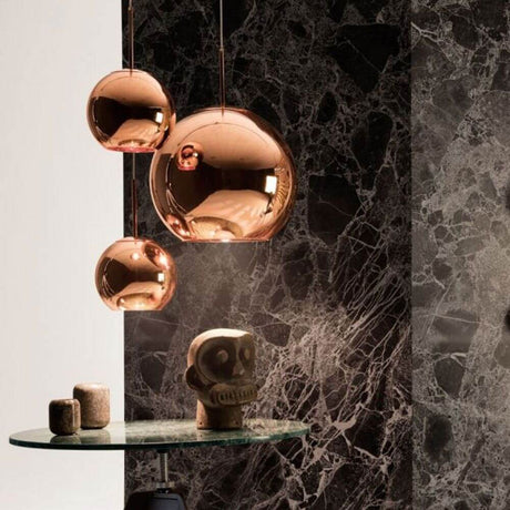 Tom Dixon Copper 3er Pendellampe Ø 78cm hängt über einem Tisch mit einer stilvollen Skulptur.