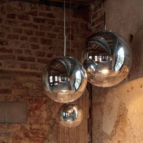 Tom Dixon Mirror Ball 3er Mobile Galerieleuchte in einer stilvollen Umgebung mit reflektierendem Licht.