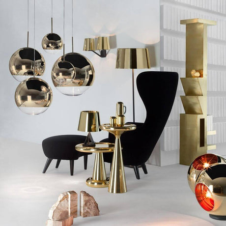 Ein modernes Wohnzimmer mit Tom Dixon Mirror Ball LED Spiegelkugel Hängeleuchte in gold und stylischen Möbeln.