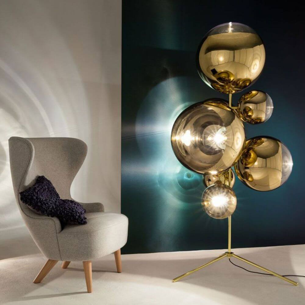 Tom Dixon Mirror Ball Stand Chandelier Stehleuchte in stilvollem Interieur neben einem modernen Sessel.
