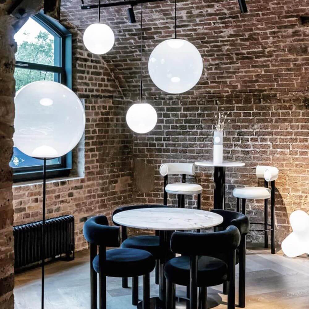 Stilvolle Innenansicht mit Tom Dixon Opal Kugelleuchte Pendel über einem modernen Esstisch.