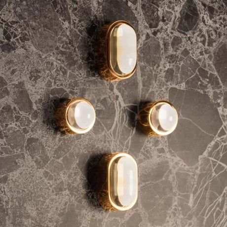Tom Dixon Spot Wandleuchte mit Glaslinse an einer marmorierten Wand, minimalistische und elegante Beleuchtung.