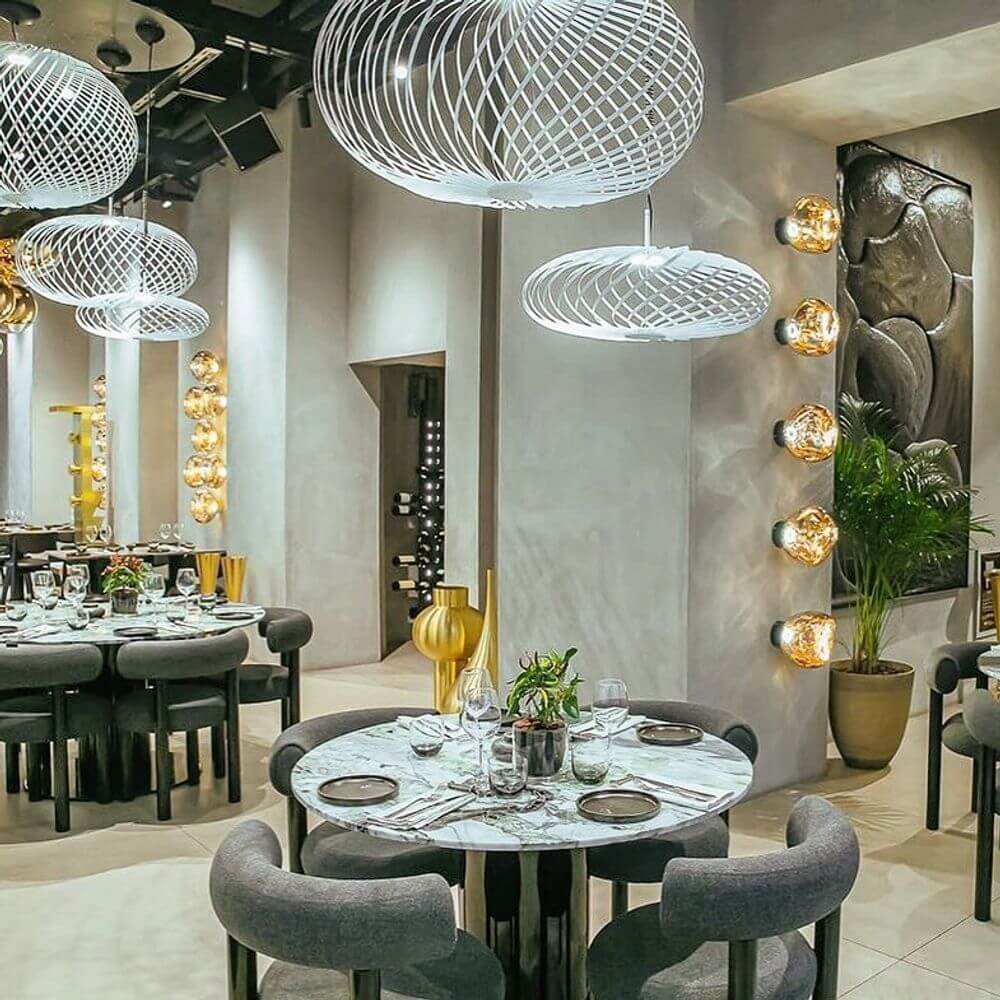 Tom Dixon Spring LED Hängelampe ausziehbar in modernem Restaurant-Design mit eleganter Tischdekoration.