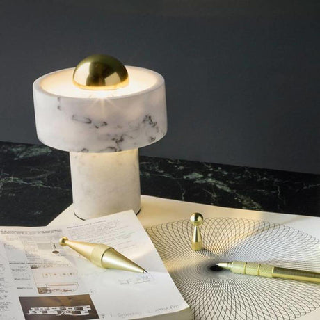 Tom Dixon Stone Tischlampe aus Marmor auf einem Tisch mit Skizzen und Zeichenutensilien.