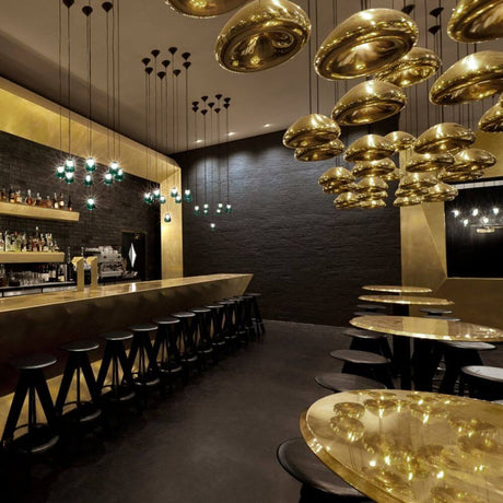 Tom Dixon Void LED Hängelampe in Gold über Bar und Esstischen in modernem Interieur