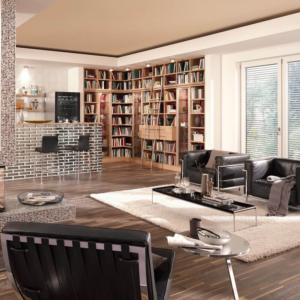 Helles Wohnzimmer mit LED Deckenlampe Puk Maxx Plus, modernen Möbeln und einer Bücherwand.