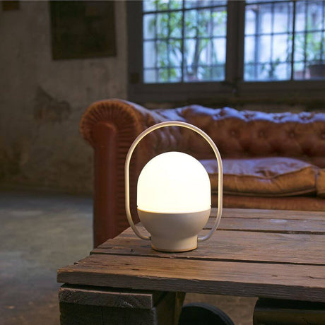 Tragbare Lampe TAKE AWAY Weiß Akku auf einem Tisch in einem modernen Wohnraum, warmes Licht und handliches Design.