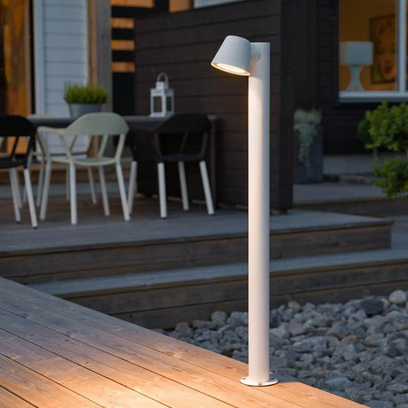 Lampione da giardino Trieste con palo bianco, acrilico trasparente, riflettore su deck in legno al crepuscolo.