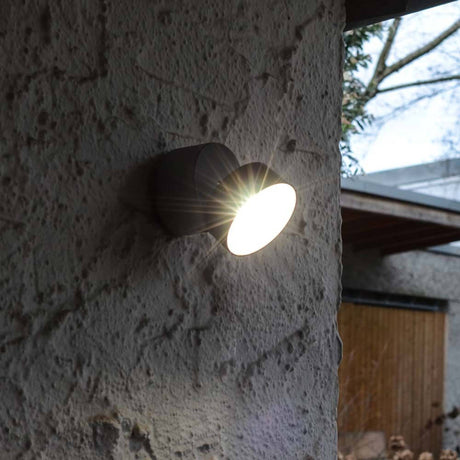 Applique murale d'extérieur LED Trumpet L orientable à 90° IP54 anthracite sur un mur avec faisceau lumineux.