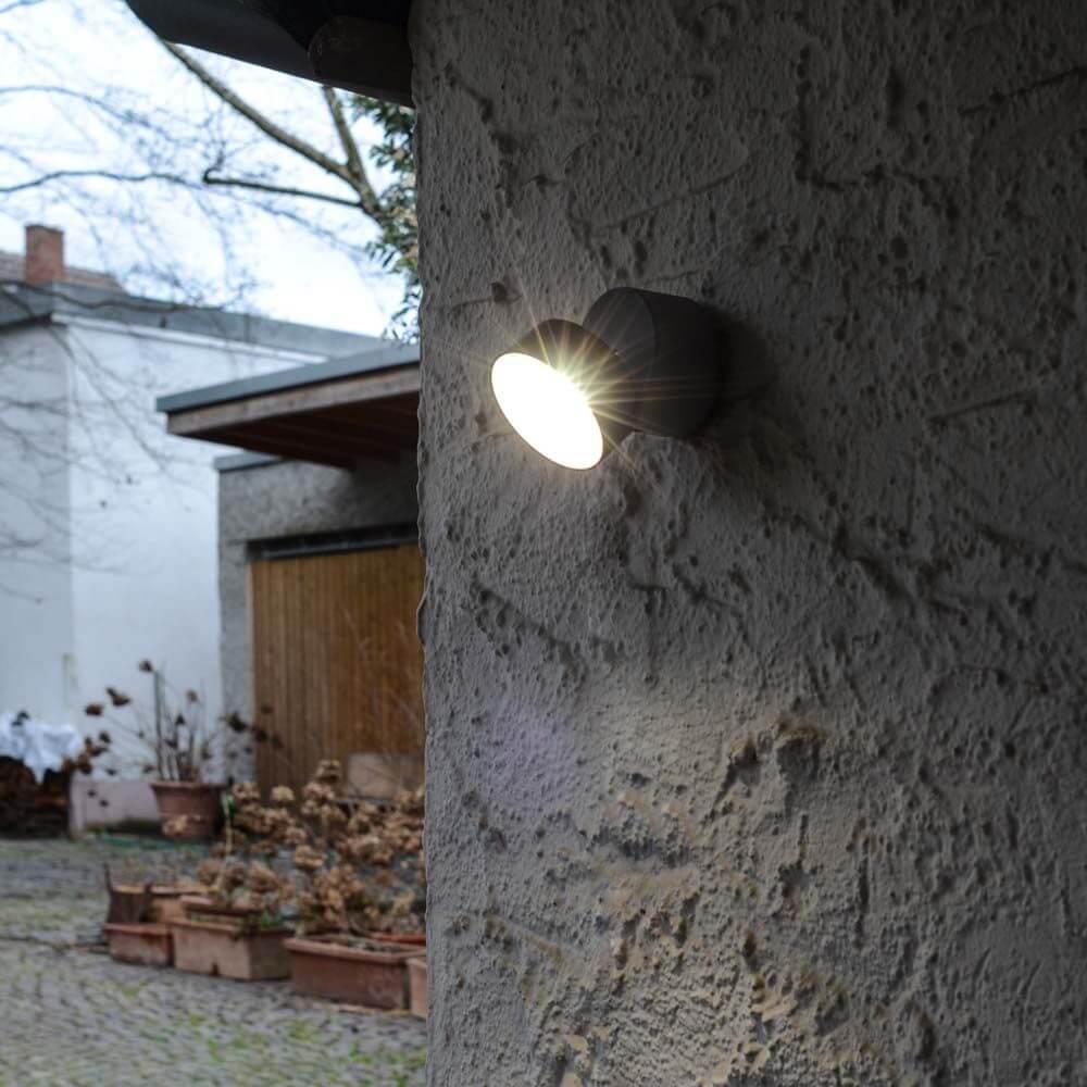 Trumpet L 90° schwenkbare LED-Außenwandleuchte IP54 Anthrazit an einer Wand mit heller Beleuchtung