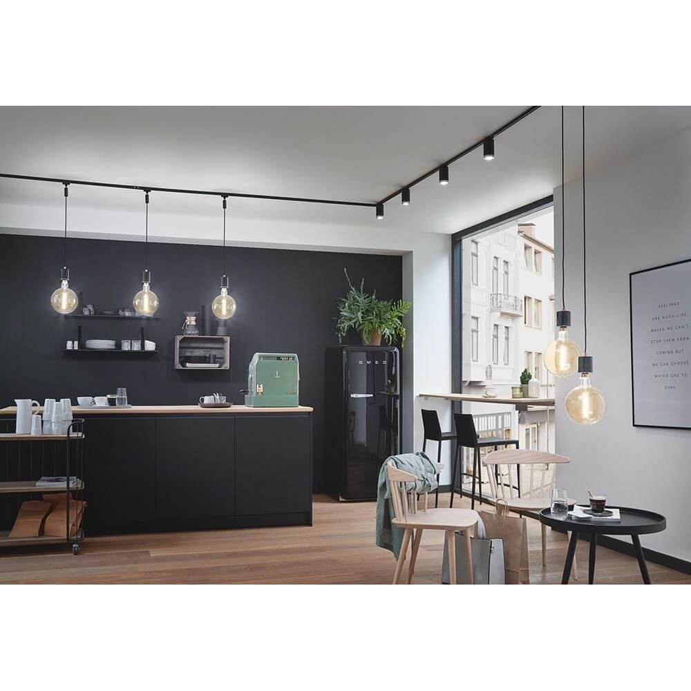 Moderne Küche mit schwarzen U-Rail Pendelleuchten und minimalistischer Einrichtung.