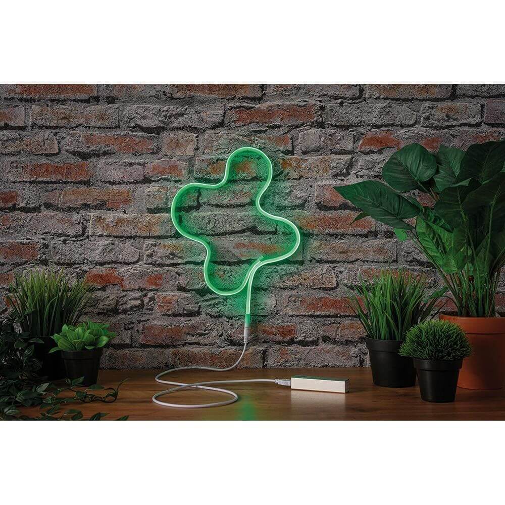 Grüner USB-LED Neon Strip in Form eines Kleeblatts vor einer Ziegelwand, ideal für stimmungsvolle Beleuchtung.