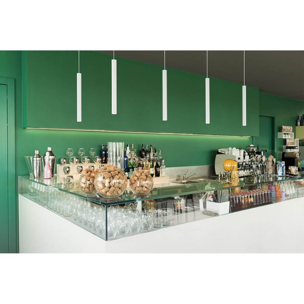 Uba Pendant LED Pendelleuchte rund Weiß 9W 3000K über einer modernen Bar mit grünem Hintergrund.