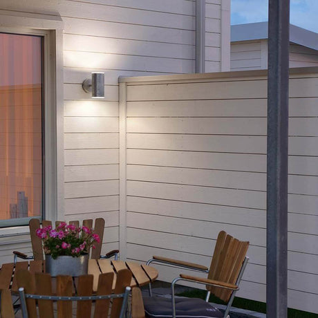 Ull LED lampada da parete esterna 3000K in acciaio zincato, vetro su una parete di casa con tavolo e sedie.