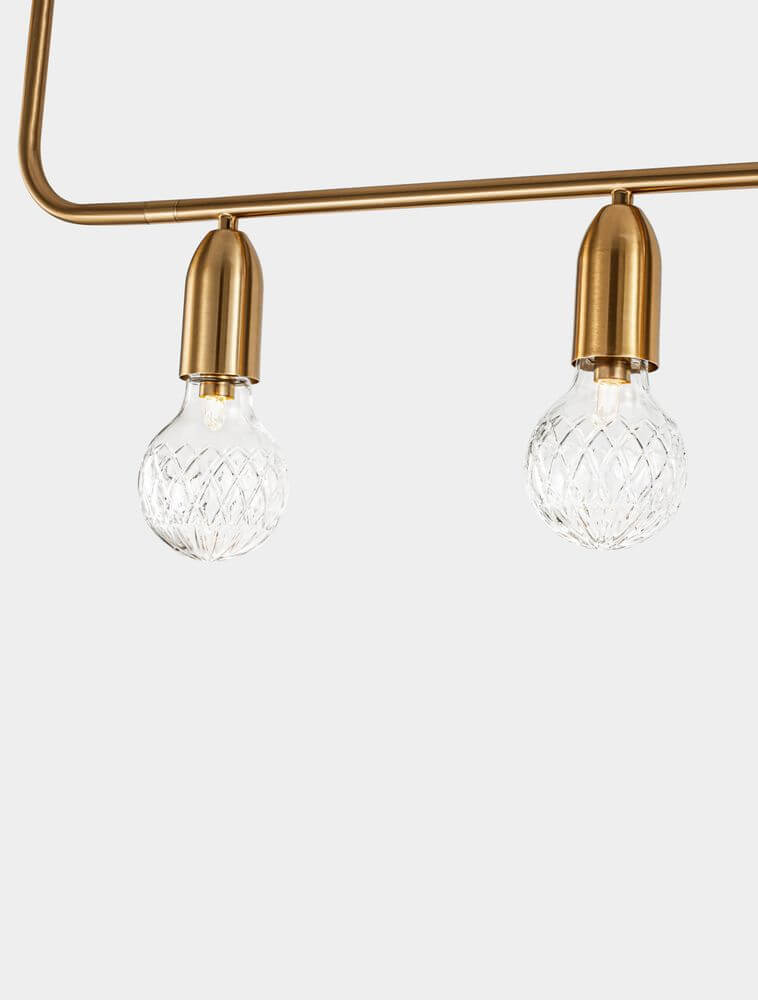 Detailansicht der Veda Pendelleuchte mit zwei eleganten Glaskugeln und einer goldenen Halterung.